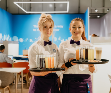 zwei Kellnerinnen mit Tablett lächeln in die Kamera