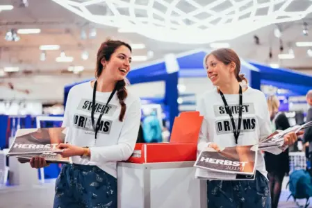 Zwei Frauen verteilen auf einer Messe die Zeitschrift für den Herbst 2018